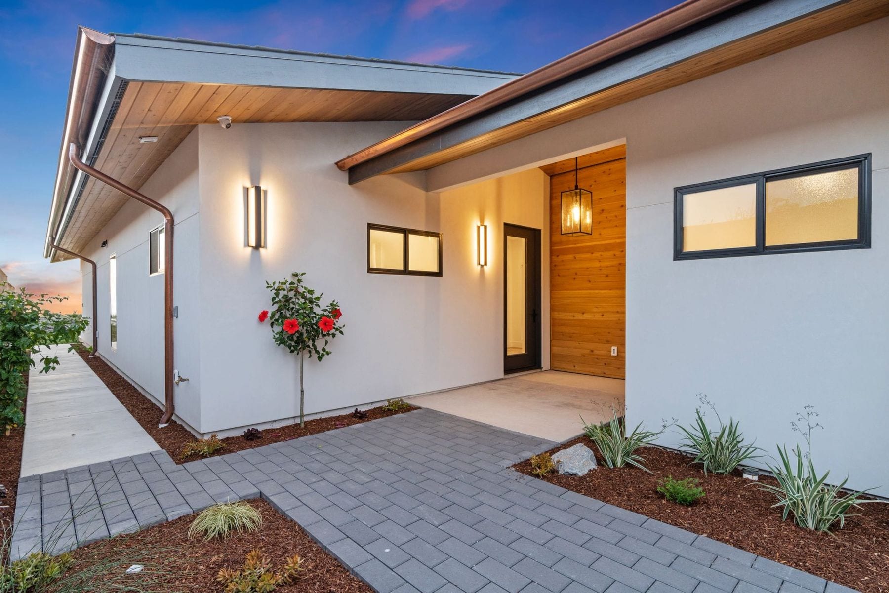 Exterior of a contemporary oceanfront house with wood and stucco walls at dusk.